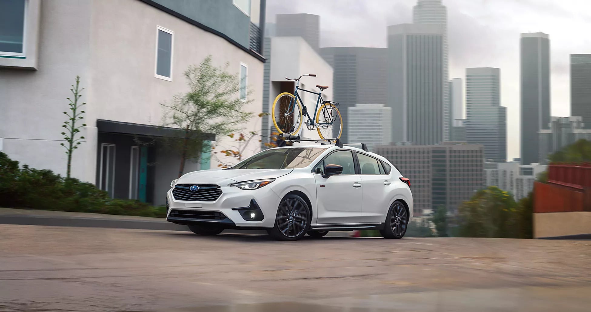 A white car sitting parked with a bike on the roof.