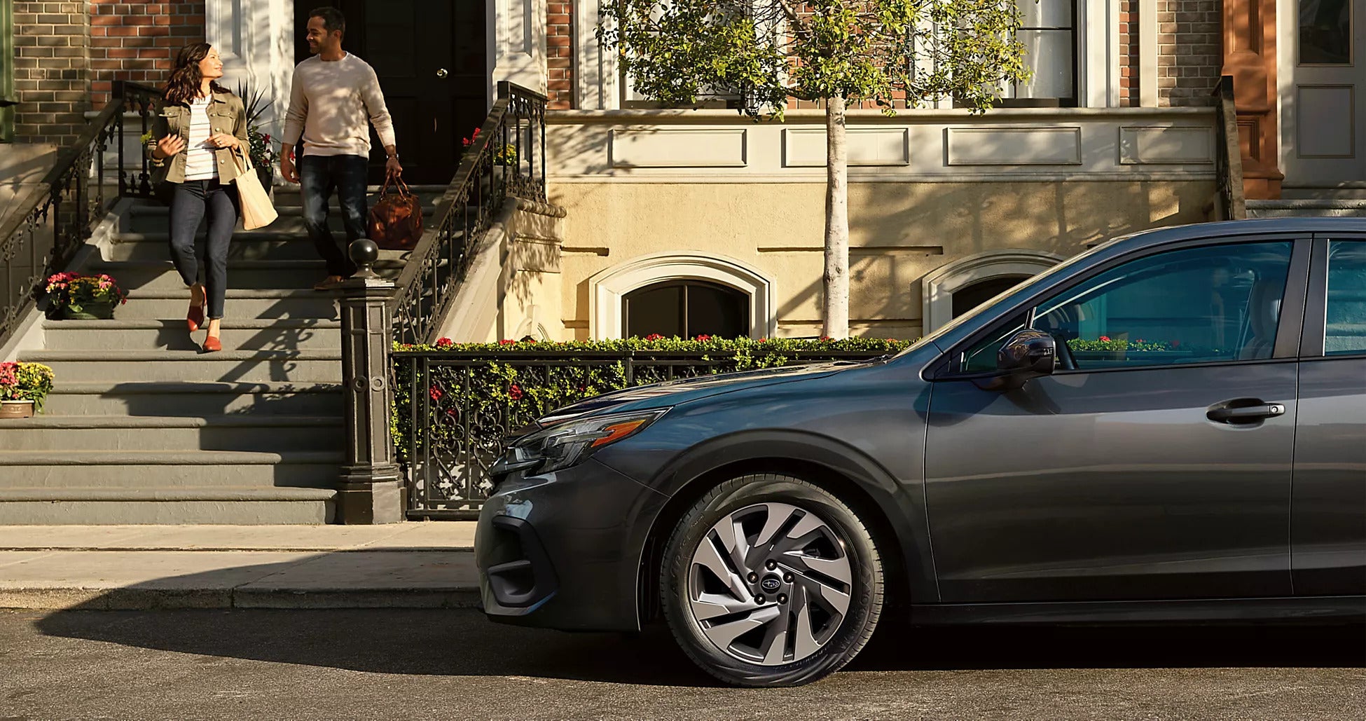 A silver car sitting parked on the side of the street.