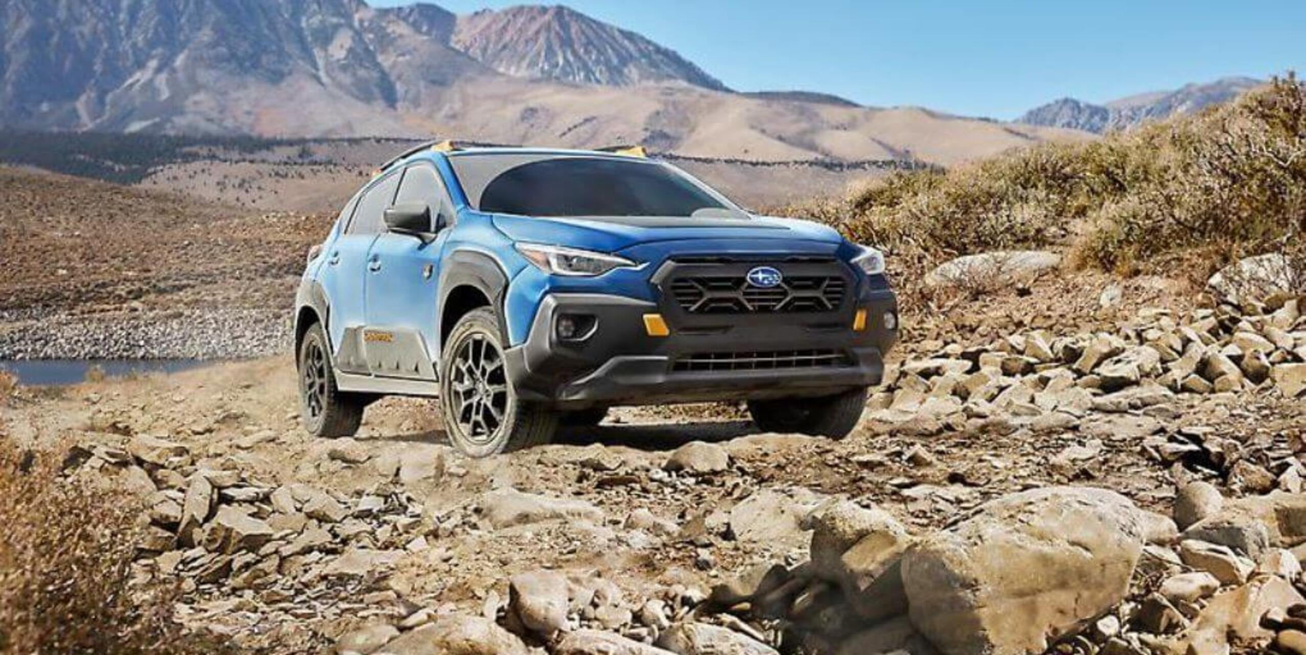 A blue car parked on some rocks.