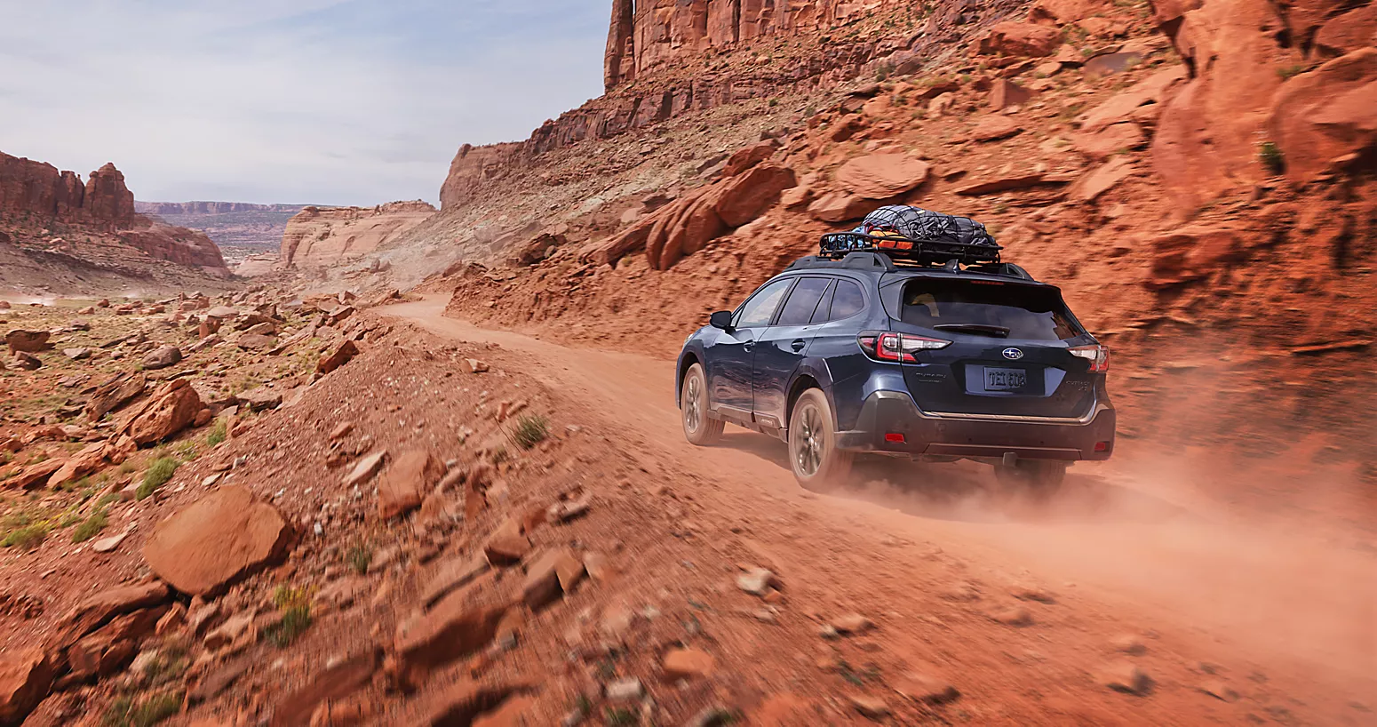 2 subaru outbacks parked on a hill overlooking mountains at dusk