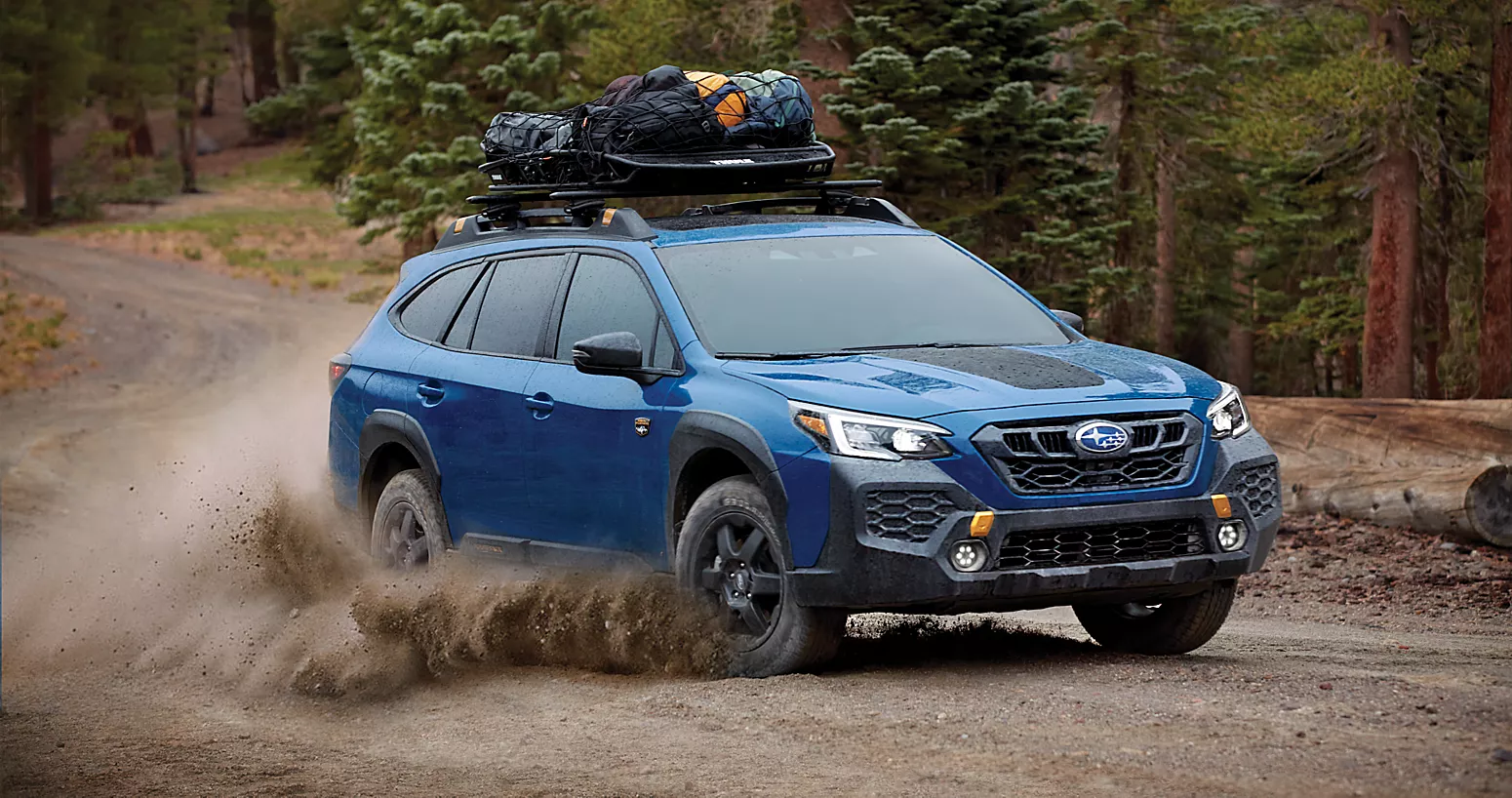 A blue suv driving on a dirt road.