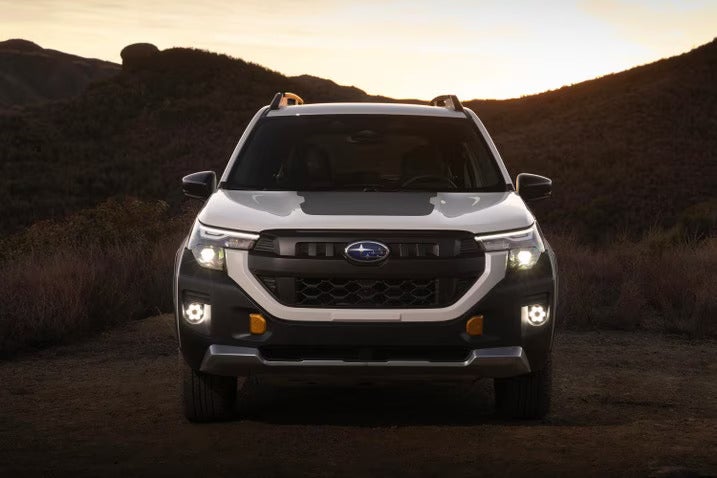 A white suv sitting parked on a dirt road.