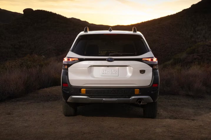 A white suv sitting parked with the rearend showing.