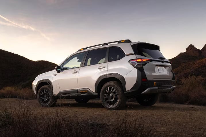 A white suv sitting parked on a dirt path.