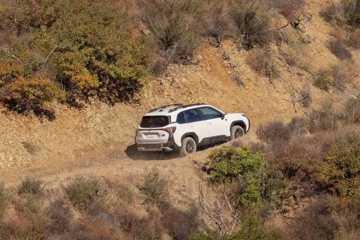 A white suv driving up a dirt hill.