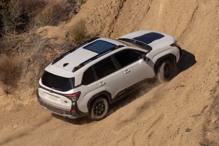 A white suv driving up a dirt hill.