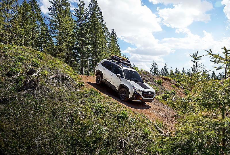 A white suv driving down a hill.